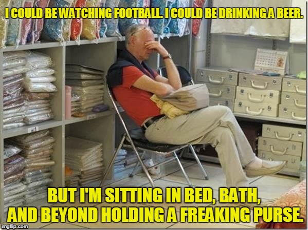 Man shopping holding a freaking purse | I COULD BE WATCHING FOOTBALL. I COULD BE DRINKING A BEER. BUT I'M SITTING IN BED, BATH, AND BEYOND HOLDING A FREAKING PURSE. | image tagged in miserable man shopping with his wife,drinking,misery,shopping | made w/ Imgflip meme maker