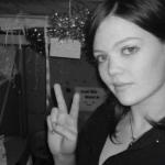 pretty girl flashes a peace sign in her dorm room