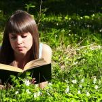 Woman Reading Book in Field of Flowers