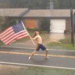 man standing with flag in hurricane