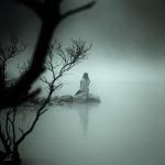 Sitting alone on a rock in a quiet foggy lake