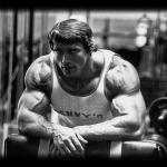 Arnold Schwarzenegger at Gym Leaning Over Bench B&W Photo
