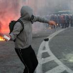 man throwing brick at riot police