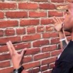 Guy looking at brick wall