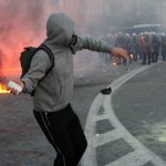 man throwing brick at riot police