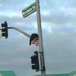 Man wearing only a coat on traffic lights pole