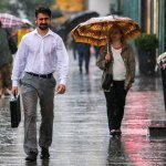 Man walking in rain woman with umbrella
