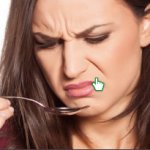 woman staring at spoon being disgusted