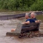 2 guys sitting on a bench in a flood