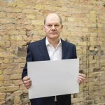 Olaf Scholz holds up a sign