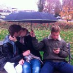 Guy holding umbrella next to couple making out