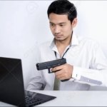 Asian dude pointing a gun at a computer