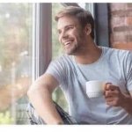 MAN WITH COFFEE SMILES OUT THE WINDOW