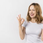 young woman biting her tongue showing ok gesture with two hands-