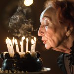 Old lady blowing out birthday cake candles