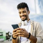 Happy man with headphones using smart phone stock photo