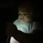 Fat baby in dark with phone