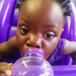 black baby drinking purple water