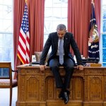 Obama sitting on desk