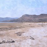 dry beach with mountains in background and rocks on sides