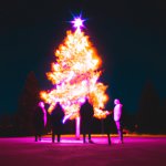 christmas tree on fire with 3 people around it