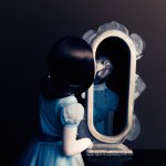 human doll looking into a broken mirror