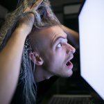 a young man pulling his hair out in front of a computer