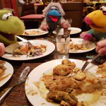 muppets eating a lot of food at a restaurant