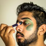 brown man putting on green makeup