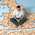 A bored-looking man sitting in the middle of a huge map depictin