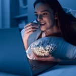 Eating popcorn while looking at computer laptop