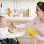 Mother Feeding Baby in High Chair