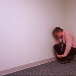 Man huddled in room corner