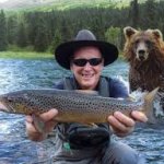 man catches fish in front of bear