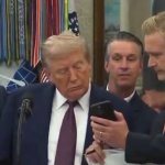 Trump looking at smartphone with JD Vance