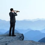 man looking through monocular on cliff