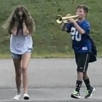 Boy playing trumpet at girl
