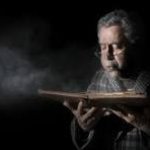 Old man blowing dusty book