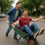 Guy pushing another guy in a wheelbarrow down the street