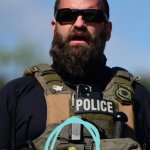 Federal agent wearing gold pin of Trump's profile meme