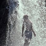 Young man under waterfall