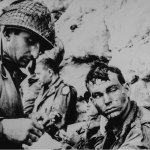 An American medical officer bandages the hand of an American sol