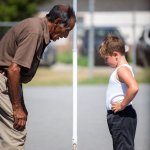 Old man and young white boy  looking at lowbar high bar