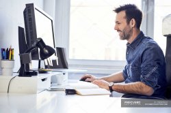 Smiling man working on computer at desk in office — casual, busi Meme Template