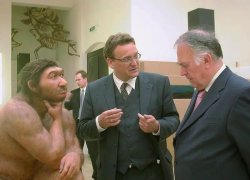 Neanderthal and two guys in a suit discussing Meme Template