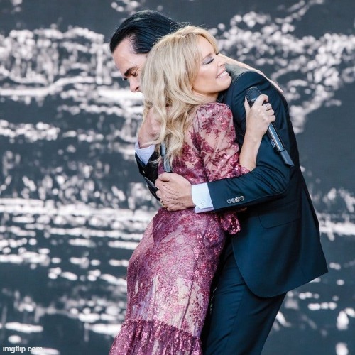 Kylie & Nick Cave hugging it out at Glastonbury. | image tagged in kylie nick cave,singers,hug,singing,pop music,musicians | made w/ Imgflip meme maker