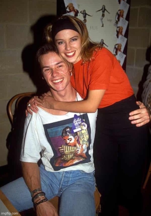 I don’t know who that is (the bloke) | image tagged in kylie young hug | made w/ Imgflip meme maker