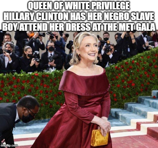 Queen does not wear masks,  only her servants do. | QUEEN OF WHITE PRIVILEGE HILLARY CLINTON HAS HER NEGRO SLAVE BOY ATTEND HER DRESS AT THE MET GALA | image tagged in hillary clinton,liberal hypocrisy,no racism,funny memes,truth,political meme | made w/ Imgflip meme maker