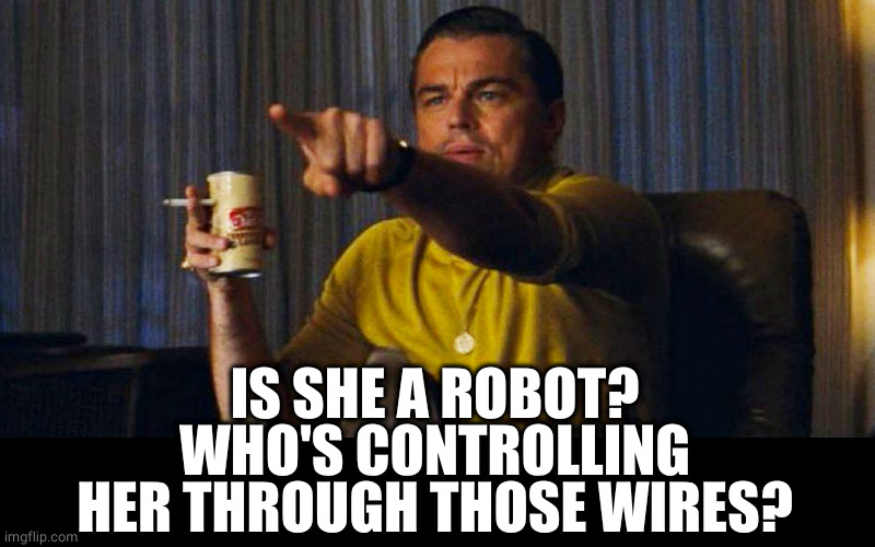 Leo pointing | IS SHE A ROBOT?
WHO'S CONTROLLING HER THROUGH THOSE WIRES? | image tagged in leo pointing | made w/ Imgflip meme maker