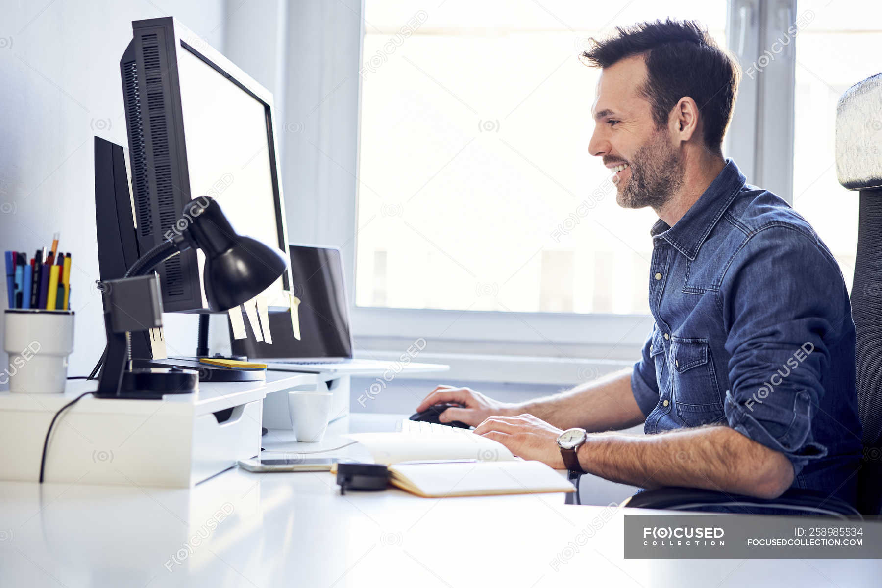 Smiling man working on computer at desk in office — casual, busi Blank Meme Template